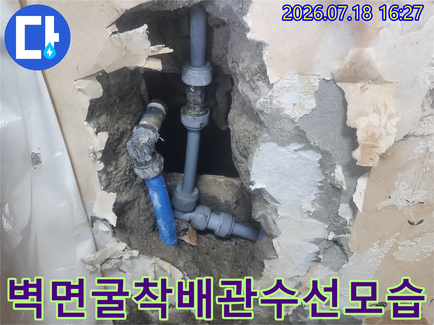 회색 벽체 속에 드러난 파란색 플라스틱 수도 관-수선 작업이 완료된 연결 부위