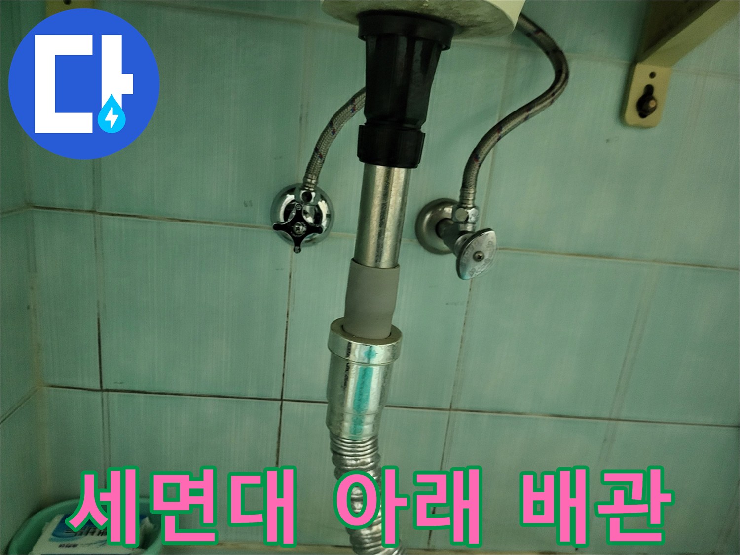 세면대 하단에 설치된-금속 재질의 급수 호스와 배수 트랩 부위