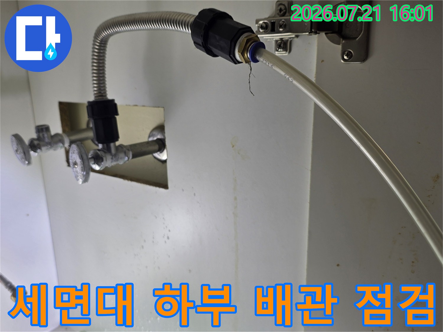 세면대 아래쪽의 은색 금속제 배관과 연결 부위를 정밀하게 점검하는 모습