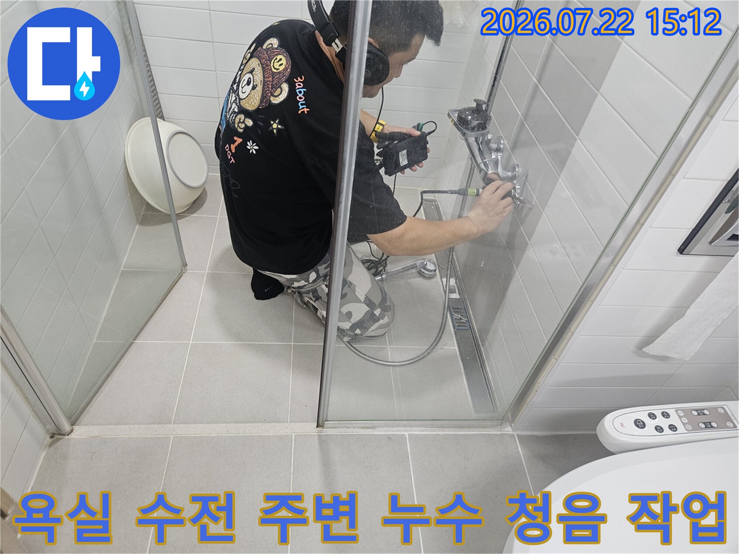 작업자가 화장실 벽면에 설치된 금속 수전 부위에서 탐지기를 사용하여 배관 상태를 진단하는 사진