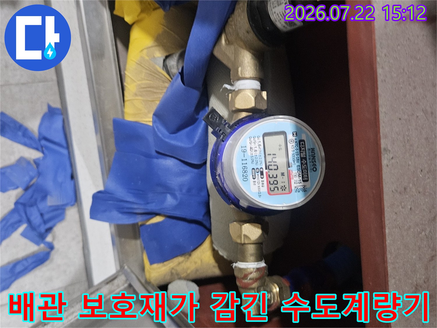 파란색-노란색 보온재와 테이프로 마감된 수도 계량기 및 밸브 장치