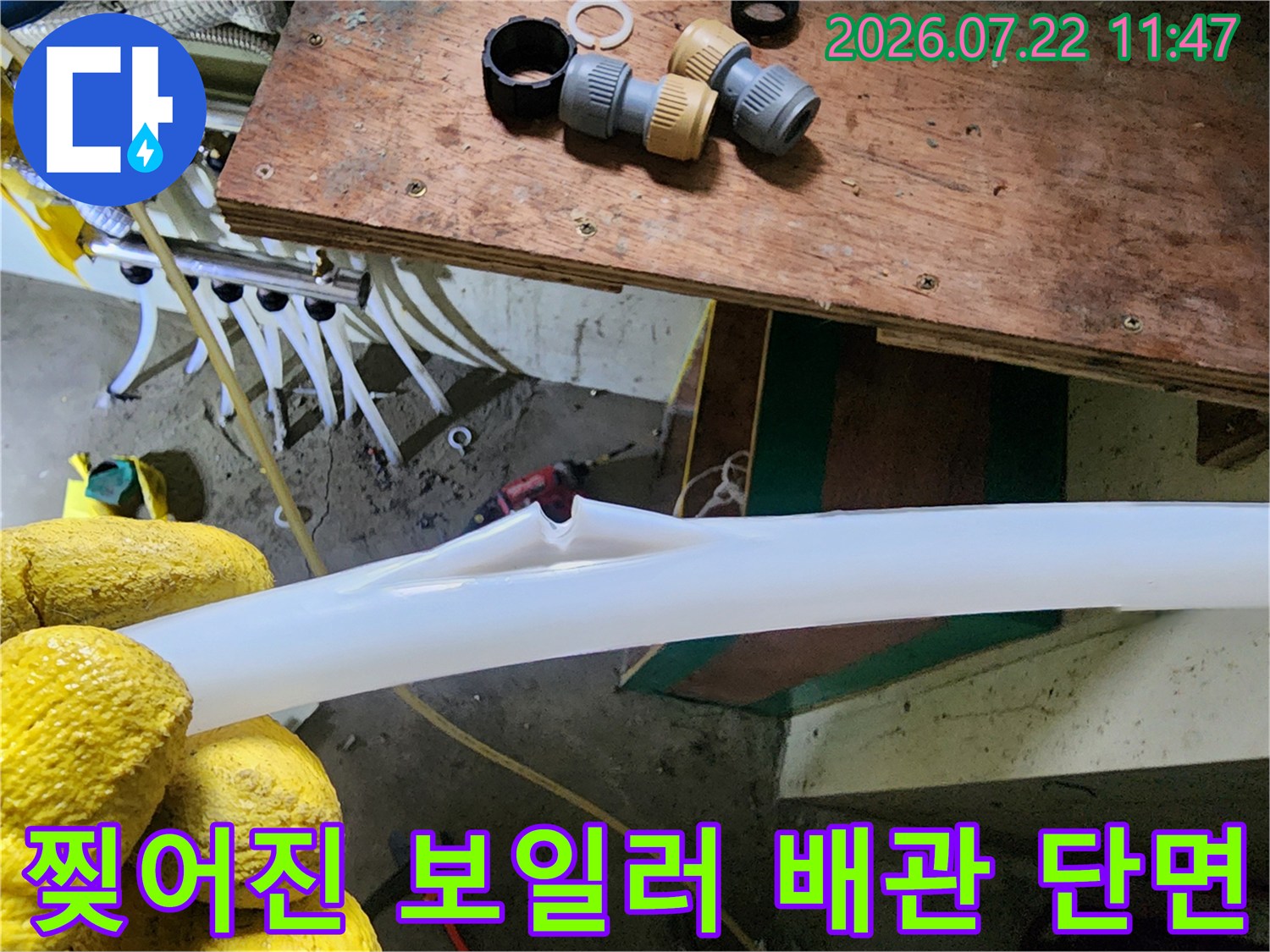 노란색 보호 장갑을 낀 엔지니어가 누수가 발생한 흰색 배관의 파손 부위를 보여주는 사진