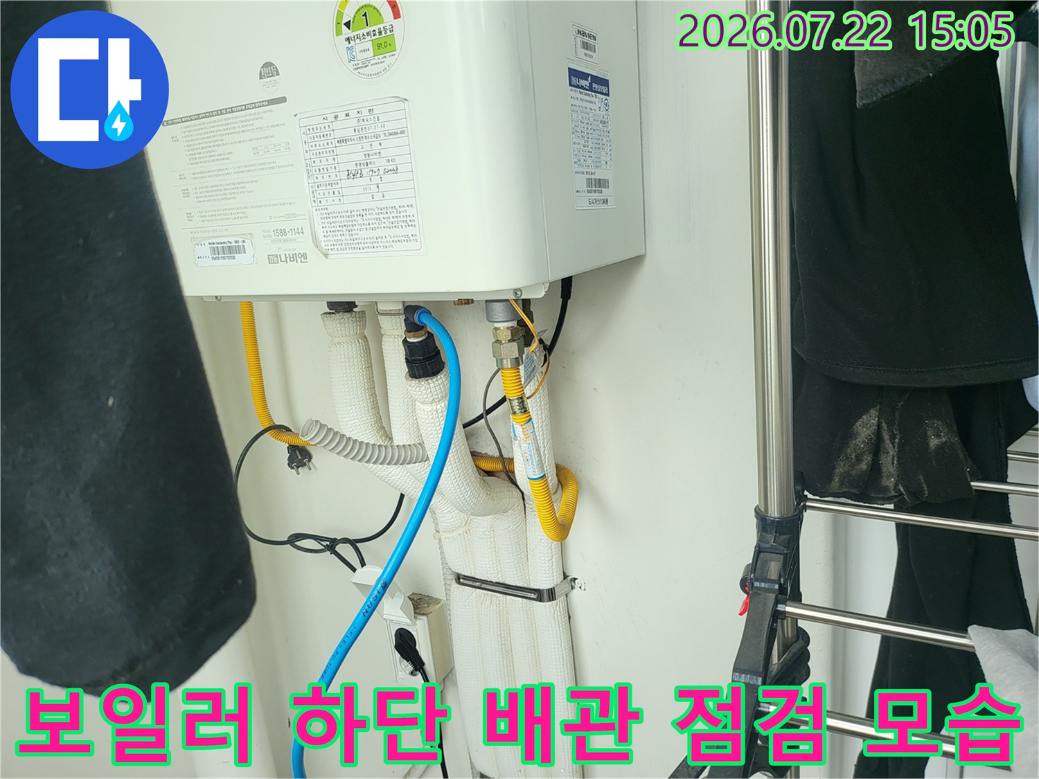 흰색 보온재로 감싸진 보일러 하단-배관 연결 부위와 파란색 호스