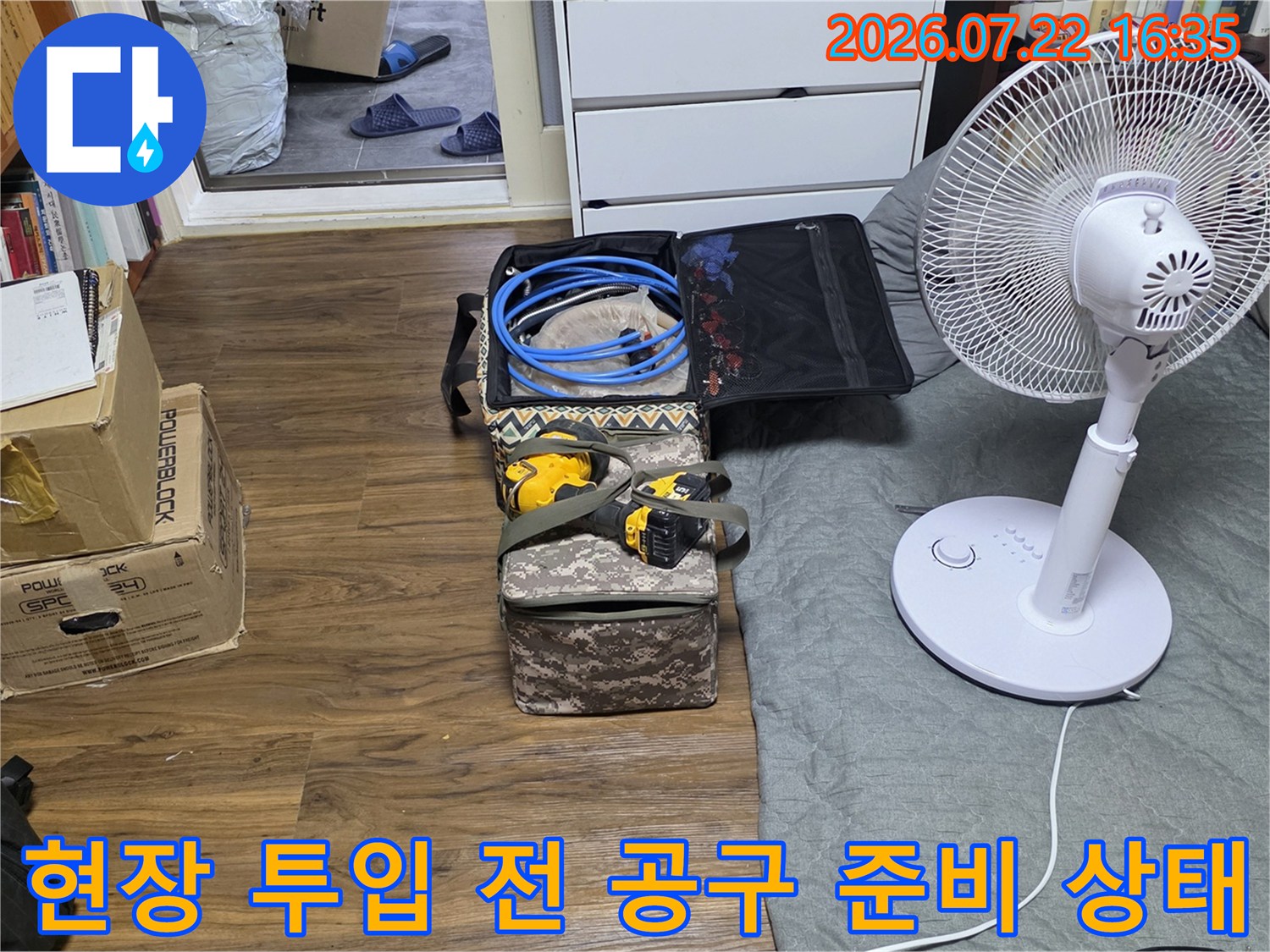 바닥에 펼쳐진 파란 배관 호스와 노란색 전동 드릴 등 누수 보수용 장비들