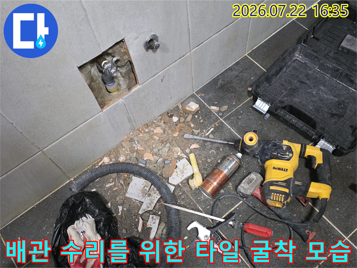 벽면-타일을-제거하고-노출시킨-수도-배관과-바닥의-작업용-공구들