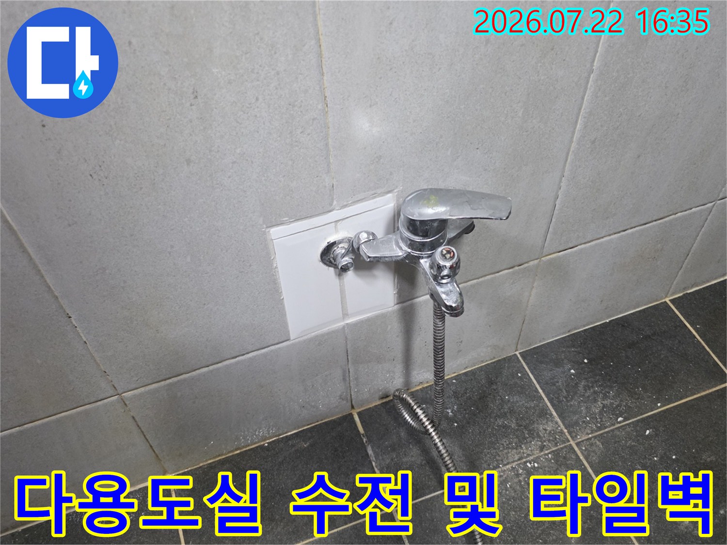 흰색 사각 타일 벽면에 설치된 수도꼭지와 연결 호스의-정면사진