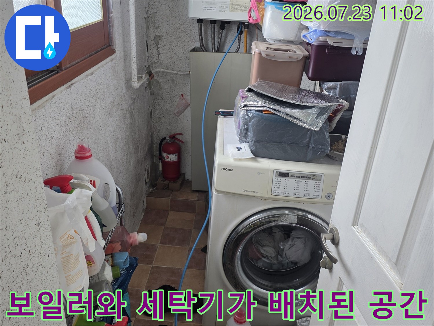 흰색 보일러-세탁기-파란색 호스가 연결된 다용도실의 전체적인 전경