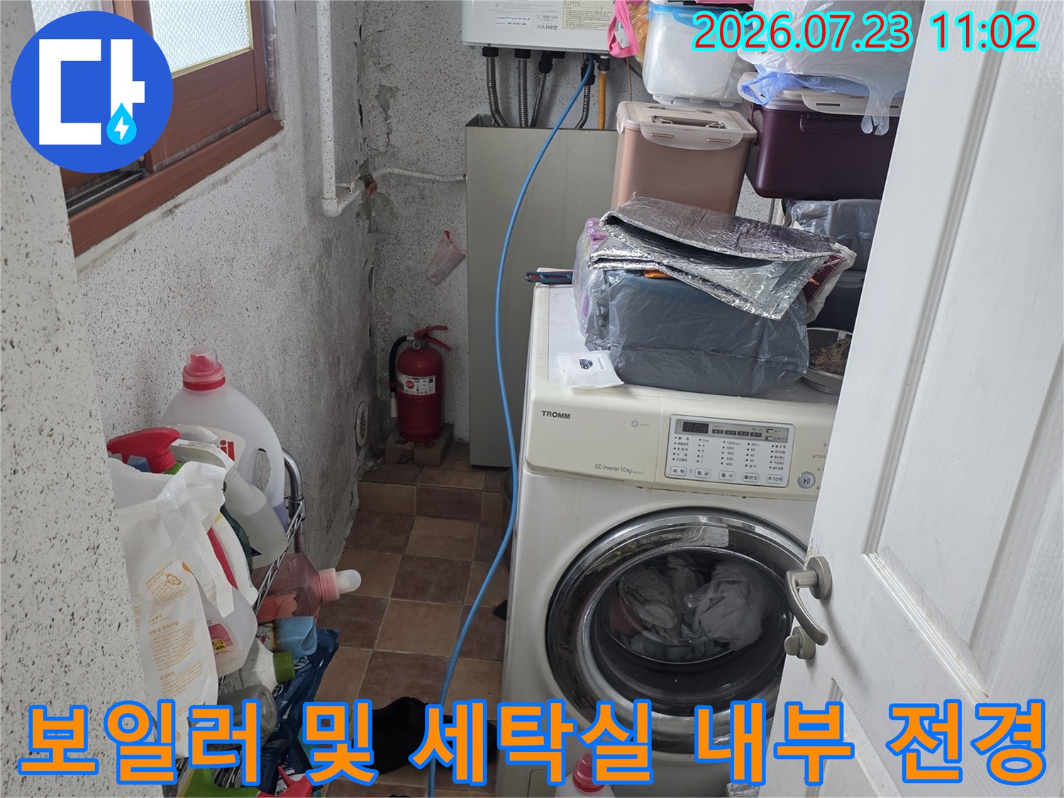 흰색 보일러와 드럼세탁기가 나란히 배치된-다용도실의 전체적인 모습