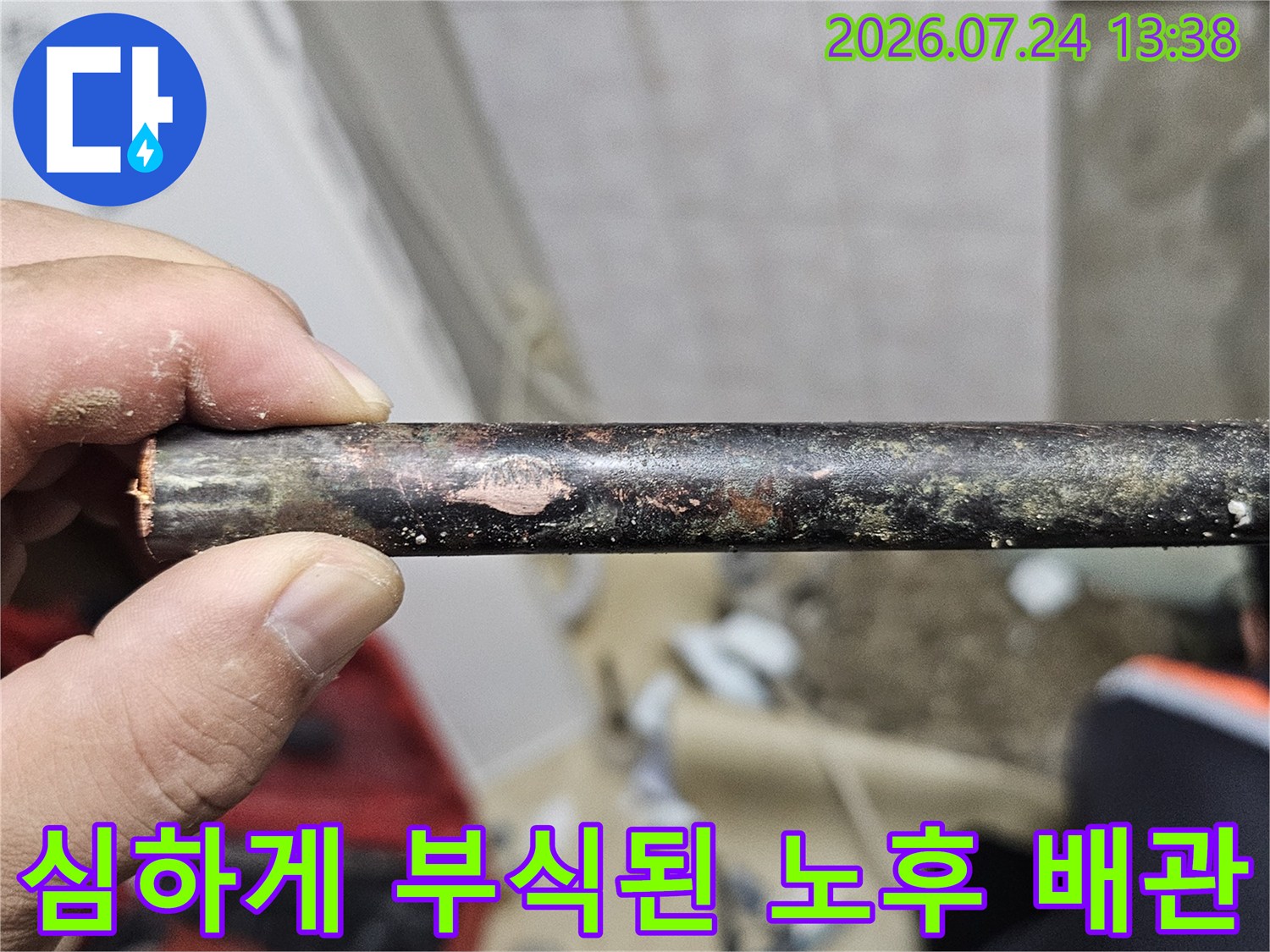 손으로 잡고 있는-표면이 검게 변하고 부식된-금속제 수도 배관 사진
