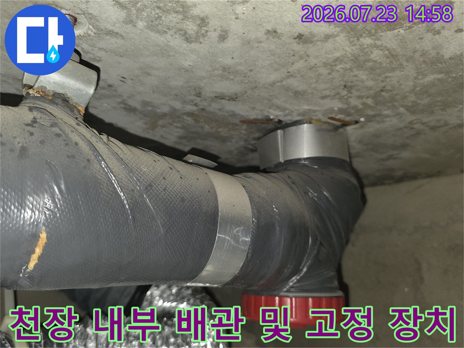 천장에 설치된 회색 배관-빨간색 연결부-금속 고정 브래킷 사진