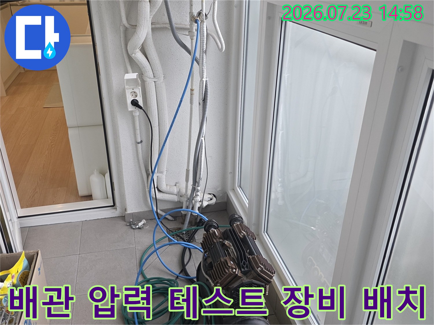 흰색 벽면의 노출 배관과 전원 콘센트 옆으로 연결된 파란색 탐지 호스-컴프레서