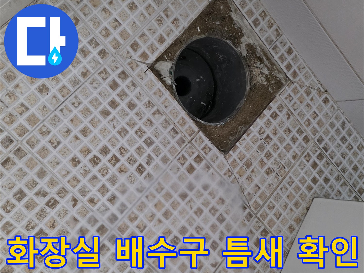 화장실 바닥 배수구 주변의 파손된 타일과 빈 공간을 보여주는 사진