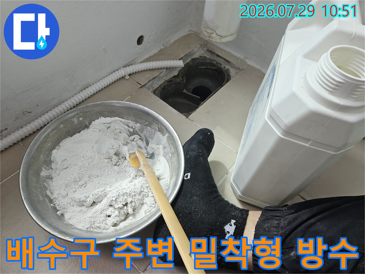 작업자의 손과 도구를 사용하여 배수구에 회색 방수재를 입히는 장면