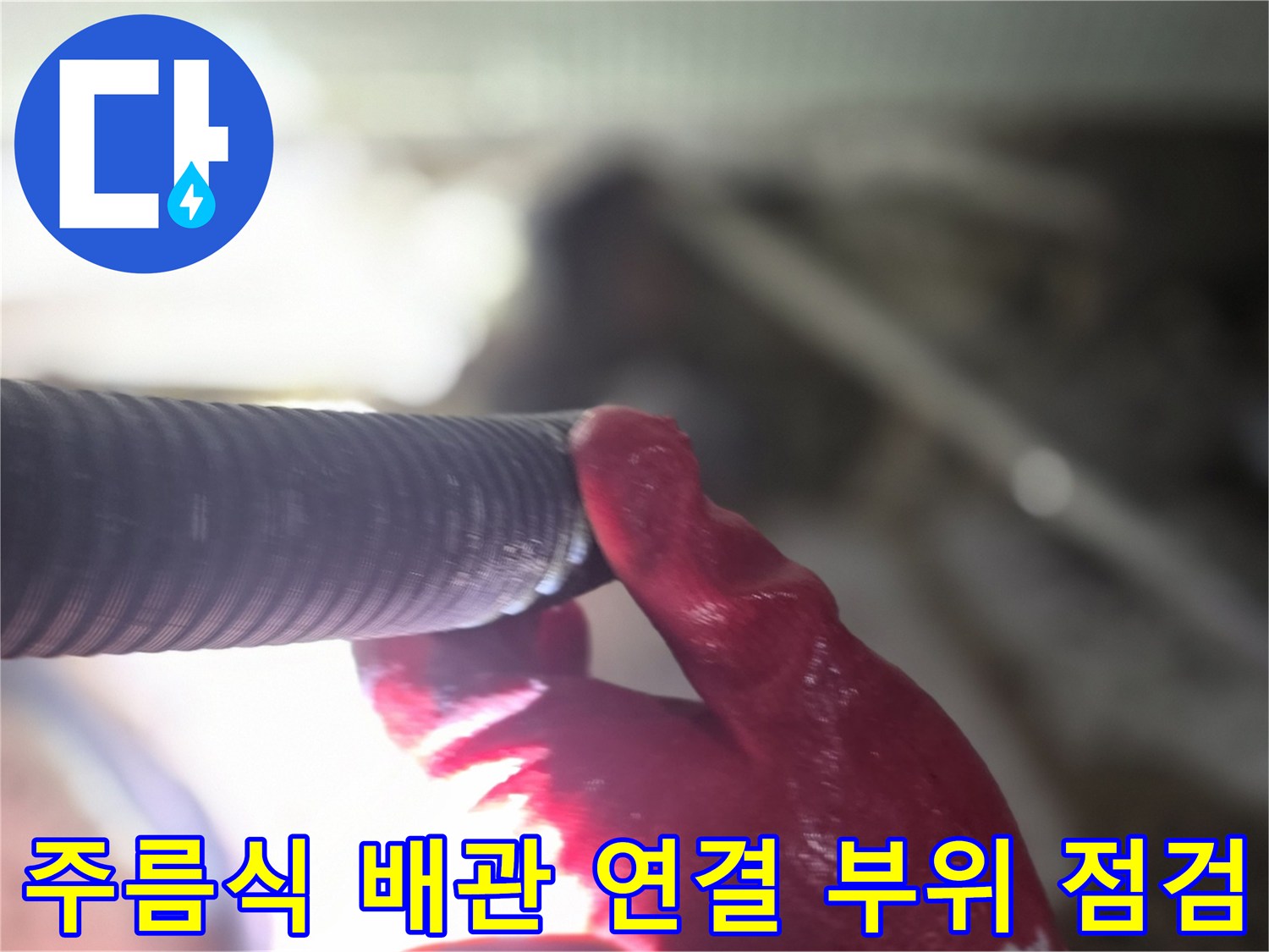 붉은색 작업용 장갑을 낀 손이 주름진 배관의 마디를 잡고 있는 모습