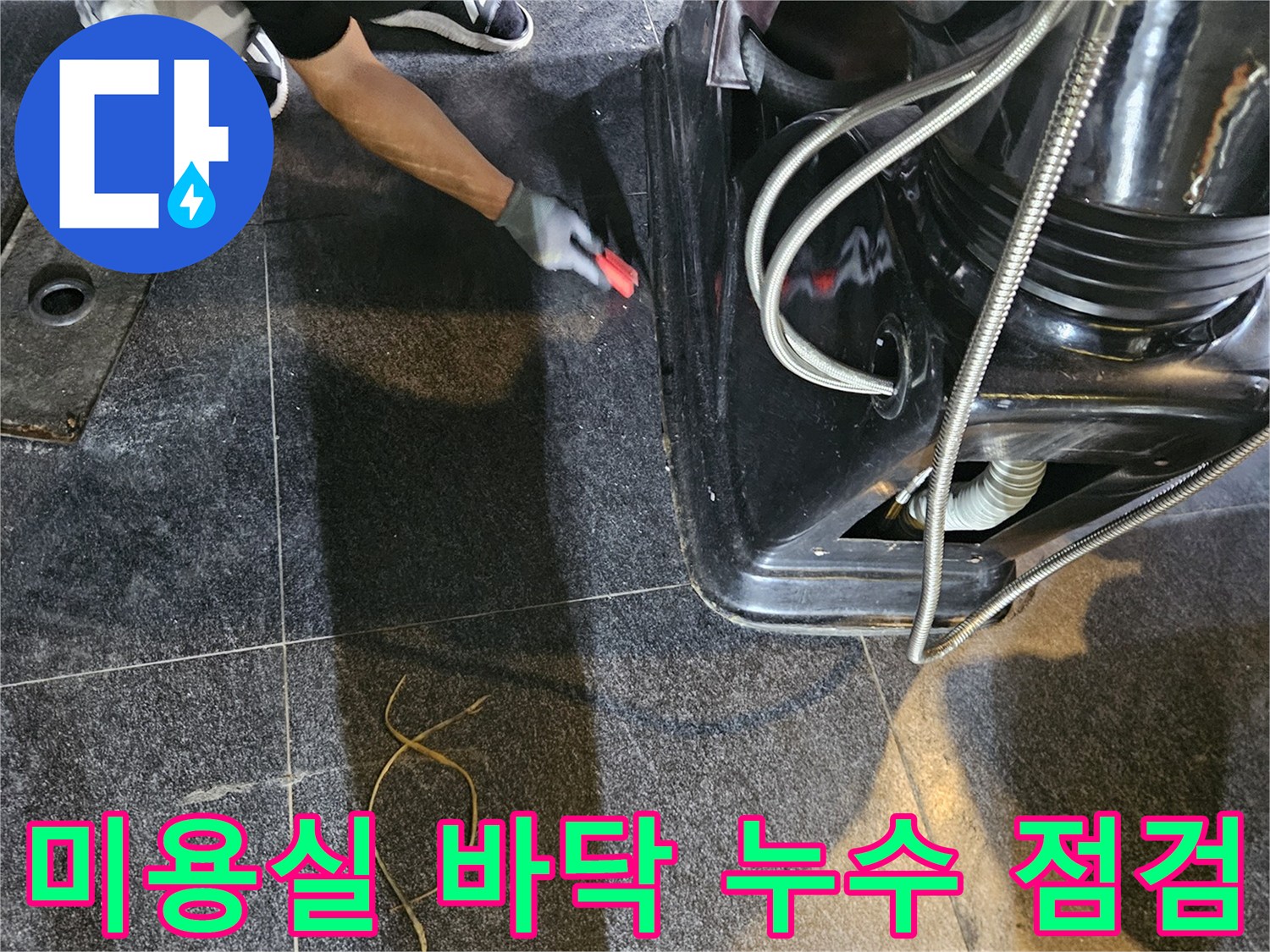 검은색 타일과 샴푸대 하단 배관 연결 부위의 근접 사진