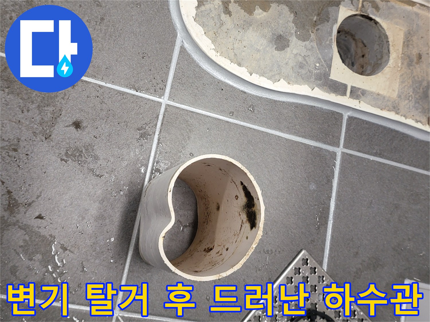 변기를 제거한 자리에 노출된 오수 배관과 젖은 바닥 마감재 사진입니다.