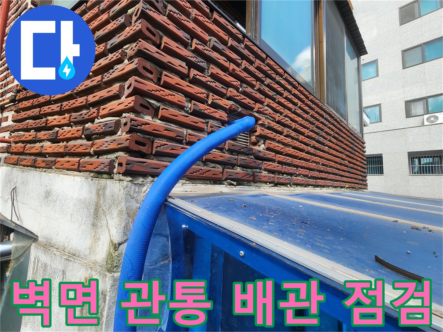 붉은 벽돌 외벽과 파란색 보임 배관의 연결 부위 사진