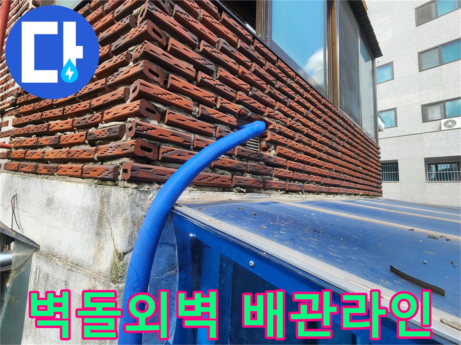 붉은 벽돌 외벽에 설치된 파란색 보온재 배관