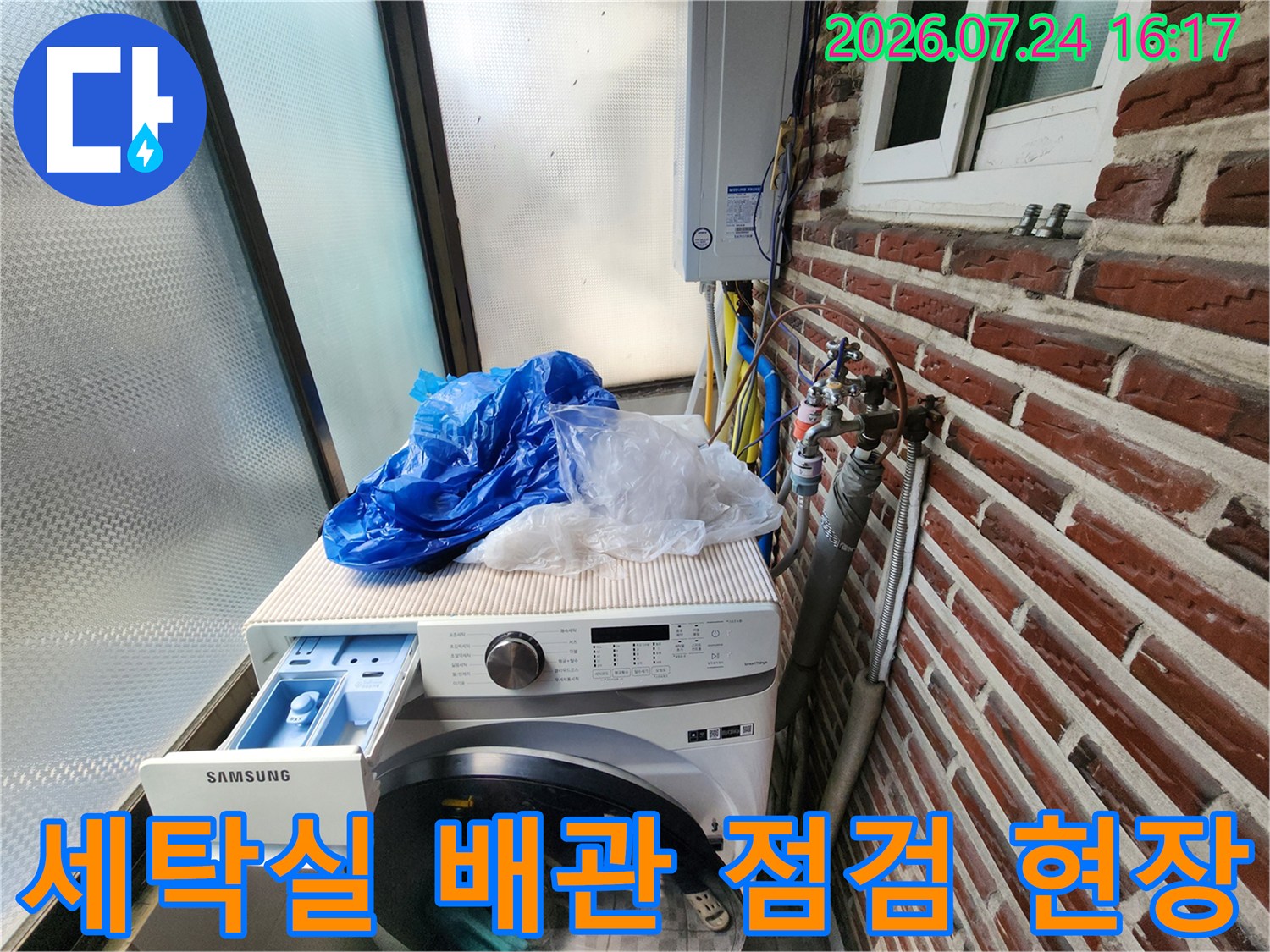 삼성 세탁기 위 노출된 수도 배관과 벽면의 붉은 벽돌 구조물