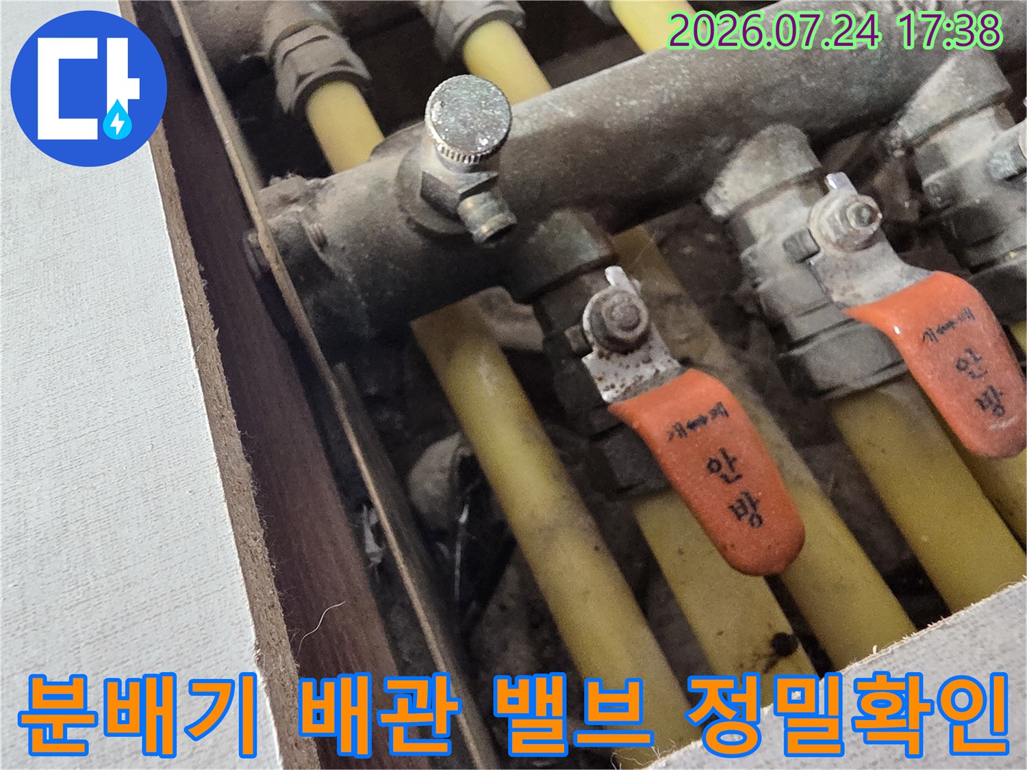 오렌지색 표시가 있는 분배기 밸브와 노출된 배관 구조