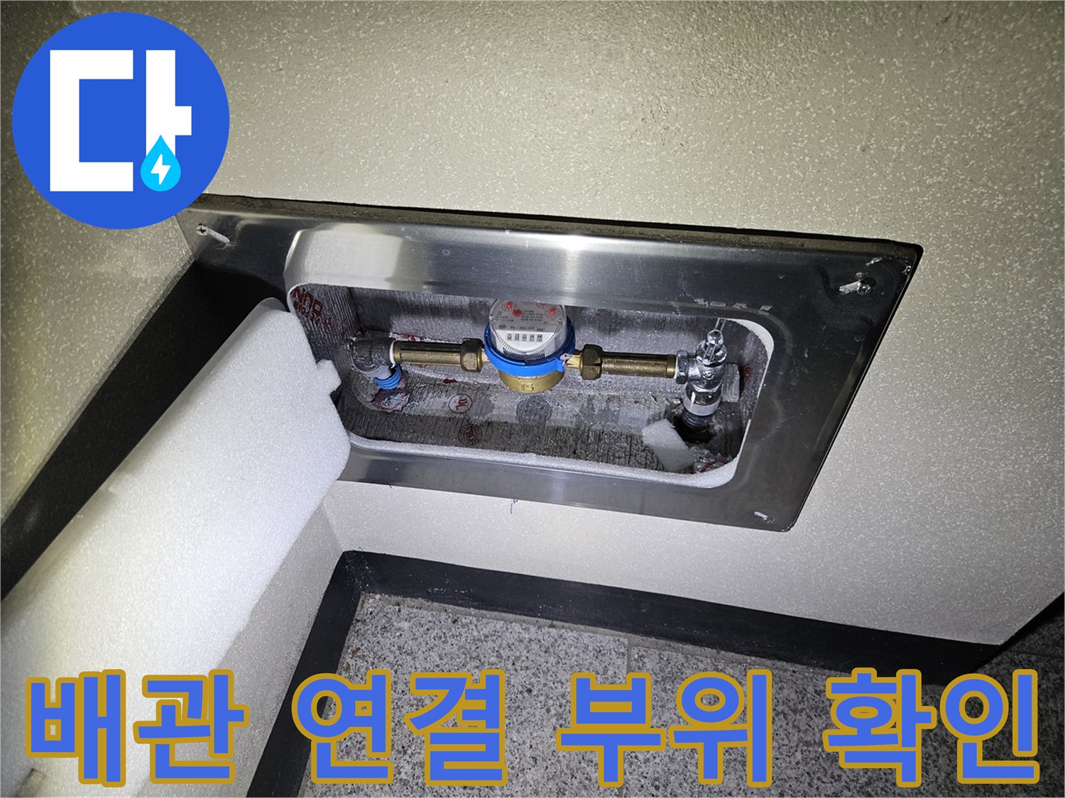 금속 점검구 내부에 노출된 수도 배관과 계량기