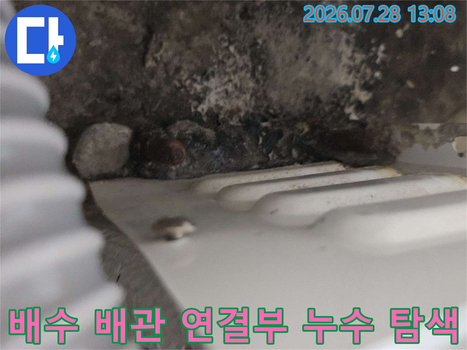주방 하부 노출된 배수 배관의 결함 부위를 상세히 촬영한 사진