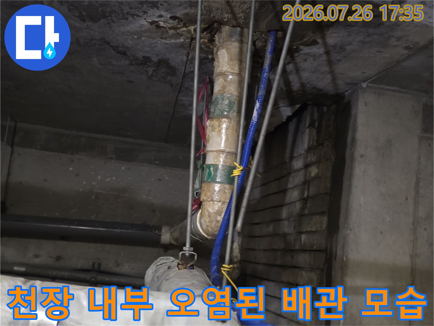 보온재로 감싸진 배관과 파란색 호스가 설치된 천장 내부의 누수 흔적