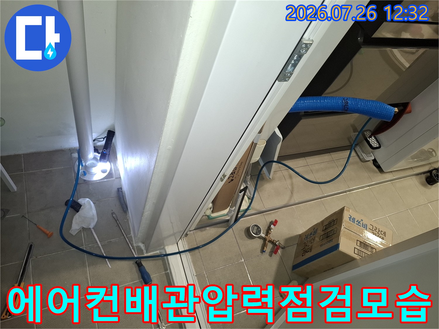 바닥 타일 위에 놓인 파란색 에어컨 배관과 공압 테스트 장비들