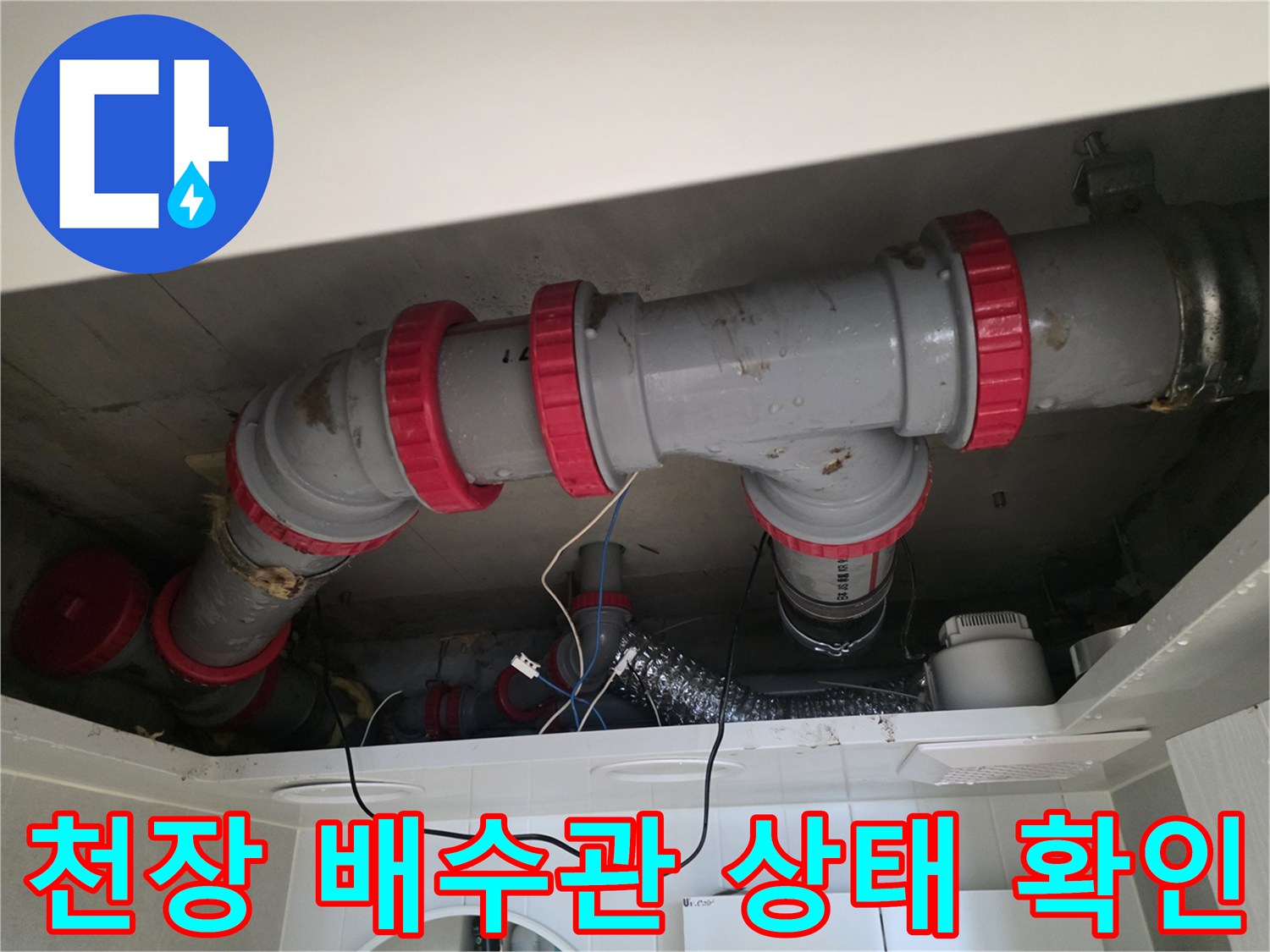 천장 내부의 회색 배관과 붉은색 연결 부품을 근접 촬영한 사진