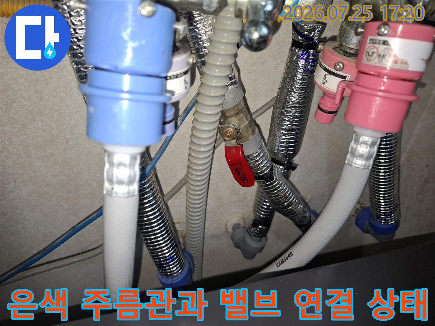 적색 핸들 밸브와 은색 주름관이 교차하는 지점의 누수 보수 작업 사진