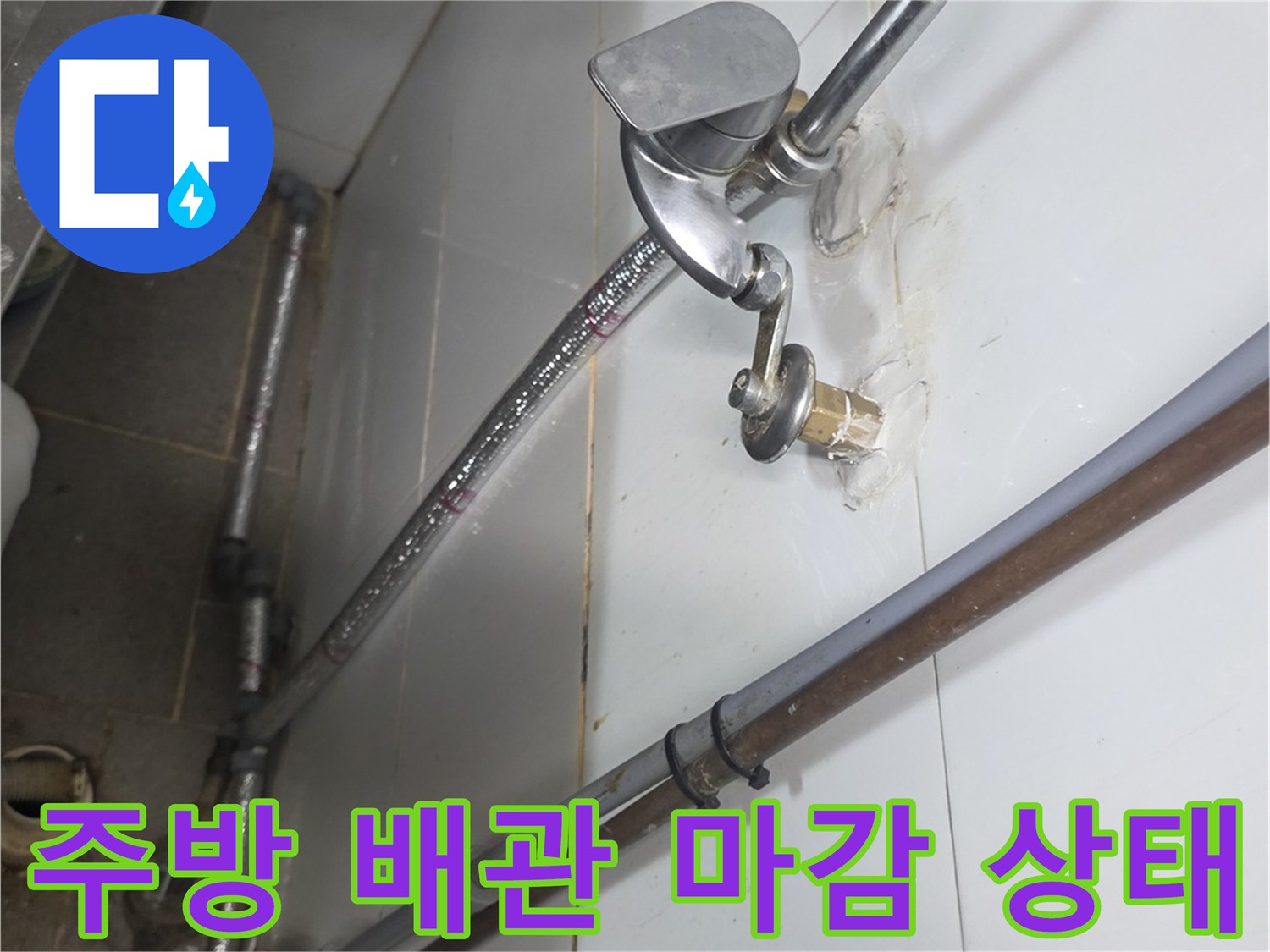 벽면 타일 사이로 연결된 금속 급수 배관의 모습