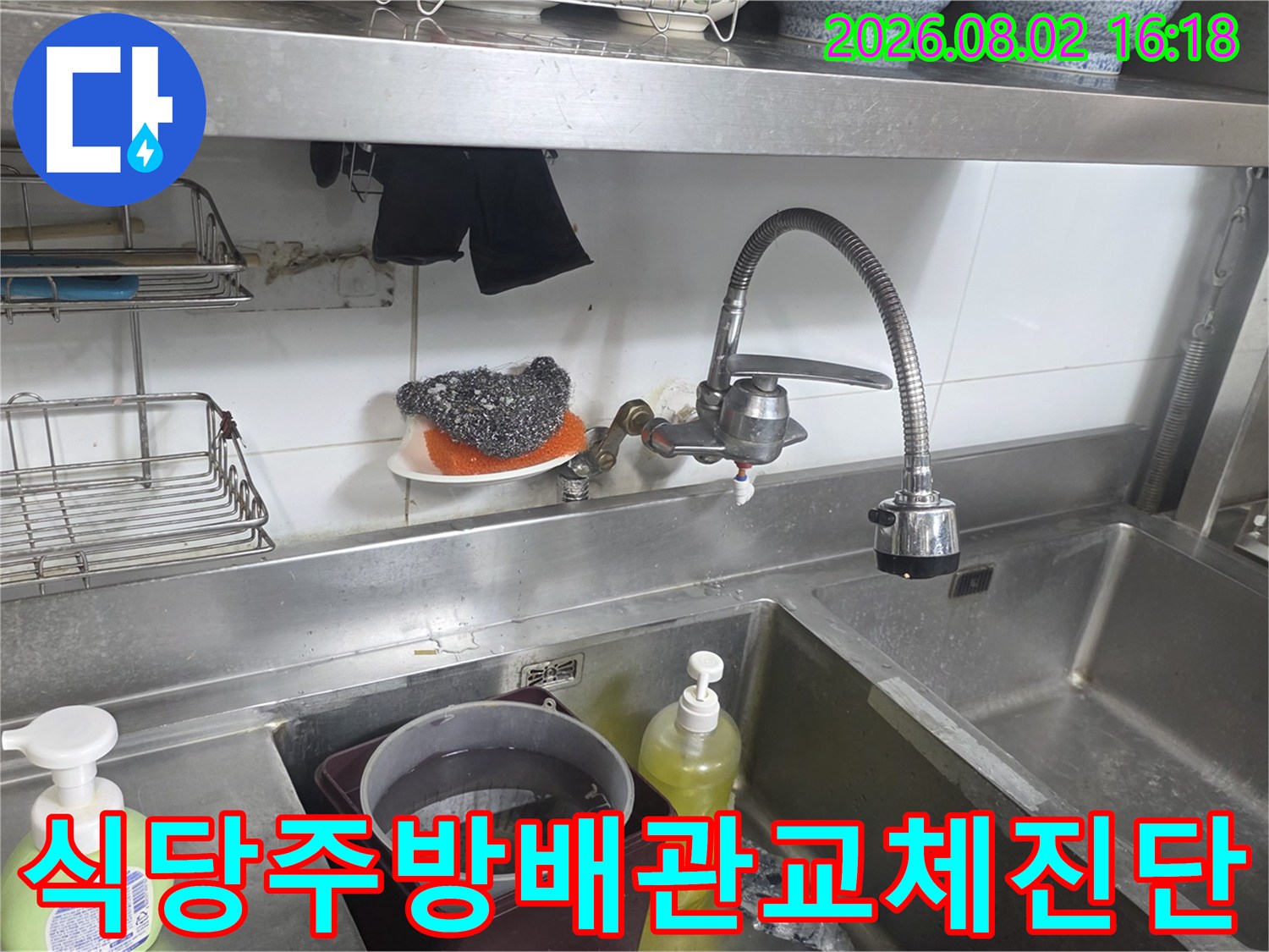 상가 주방 싱크대 아래 노출된 수도 파이프와 세척용품 주변 모습