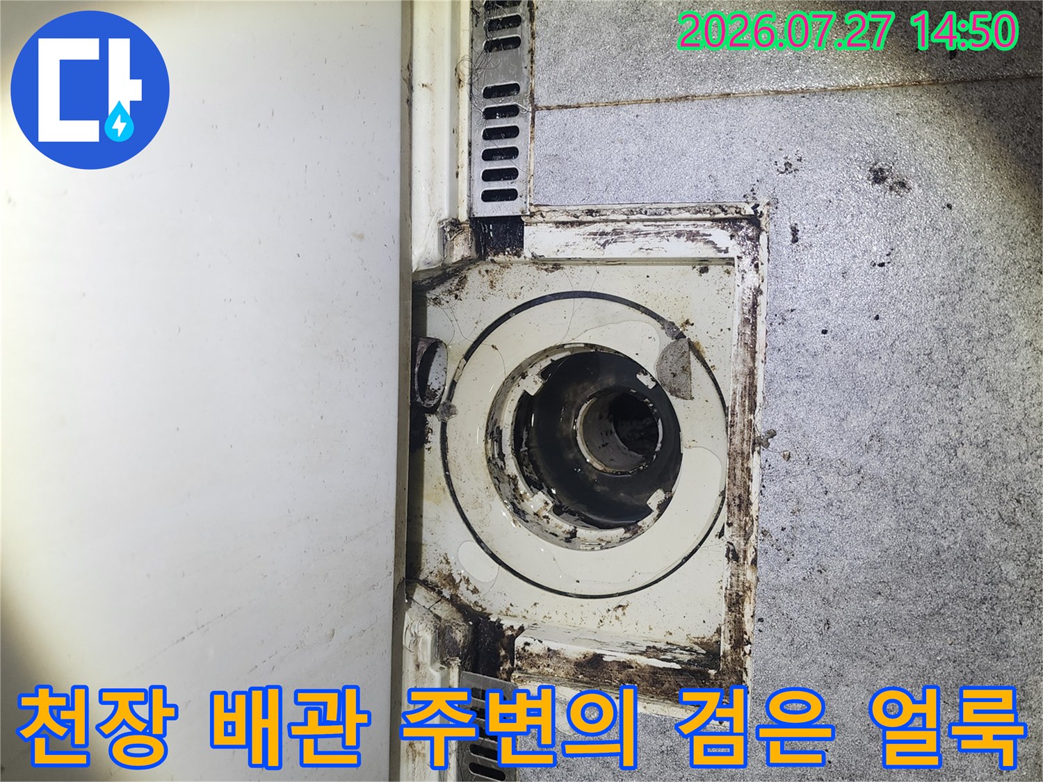 하얀색 천장 마감재 중앙에 위치한-오염된 원형 배관 연결 부위