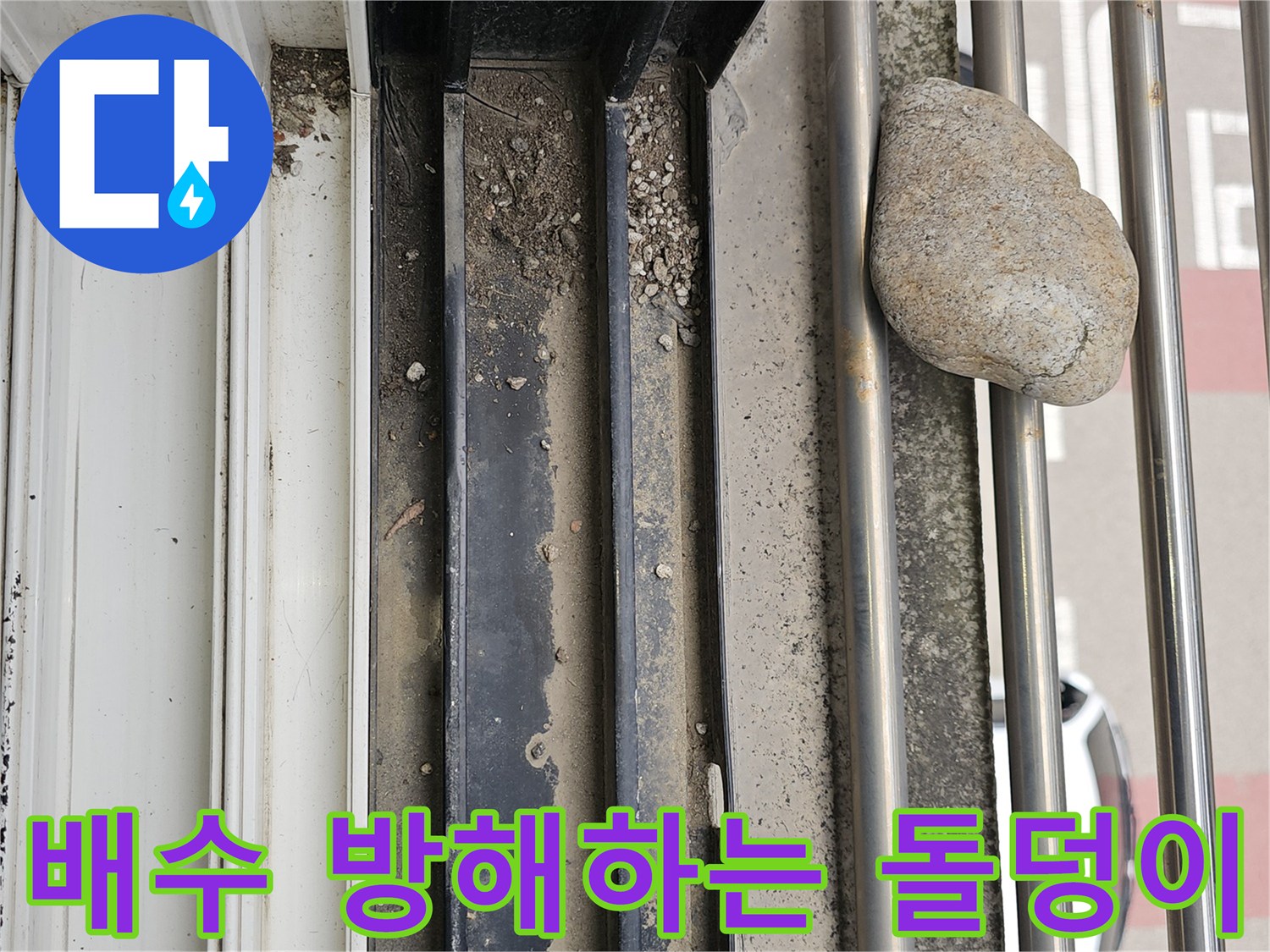 금속 난간 구조물 사이에 끼어 있는 커다란 돌과 퇴적물
