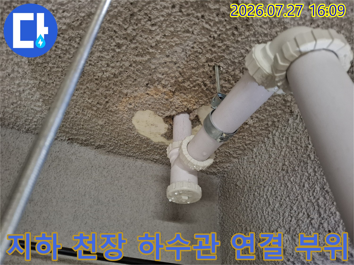 흰색 배관의 꺾임 부분과 고정 장치 그리고 주변 콘크리트 천장의 상세 모습