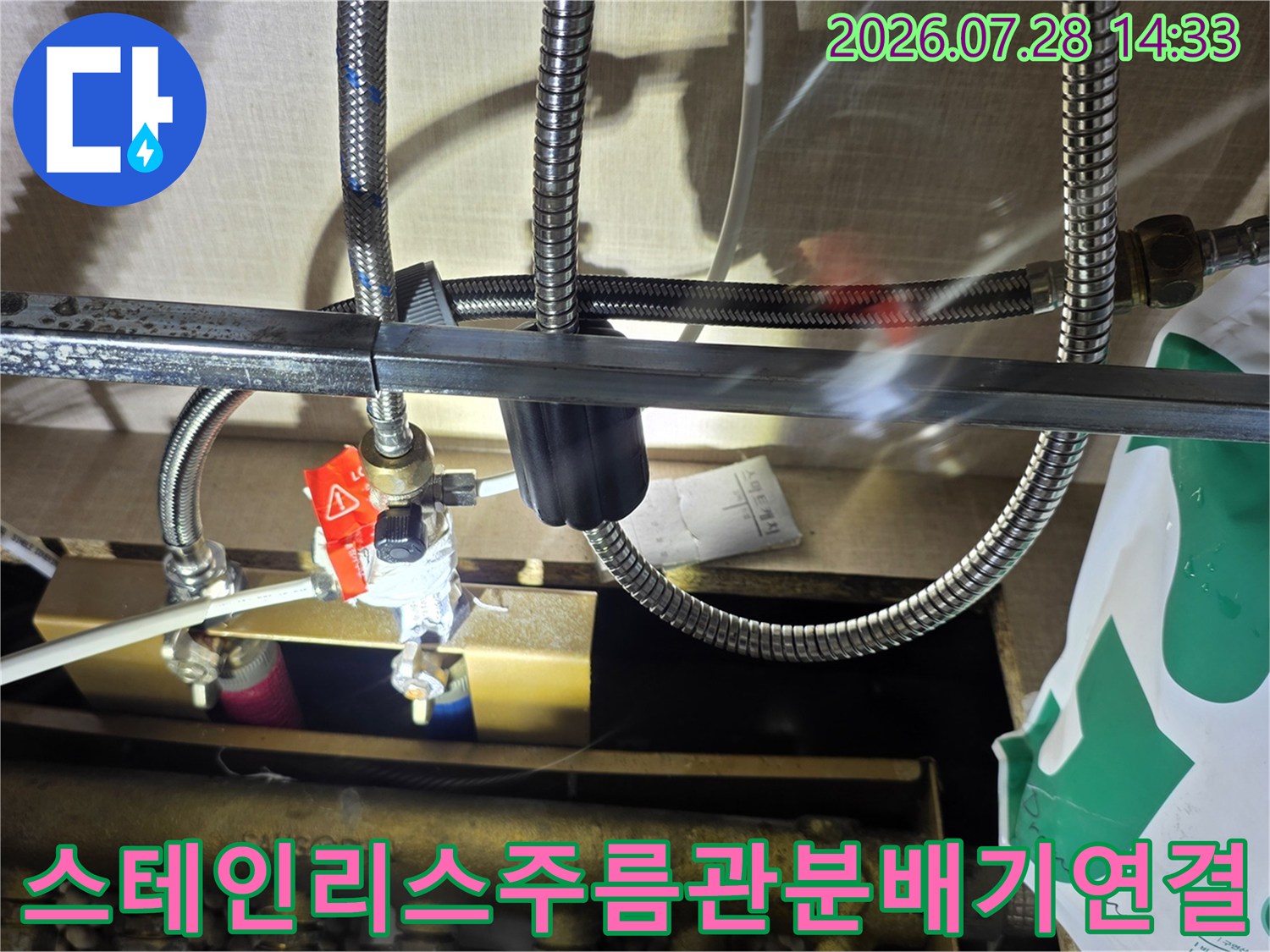 금속 분배기에 여러 가닥의 스테인리스 주름관이 연결되어 있고 붉은색 밸브가 부착된 모습