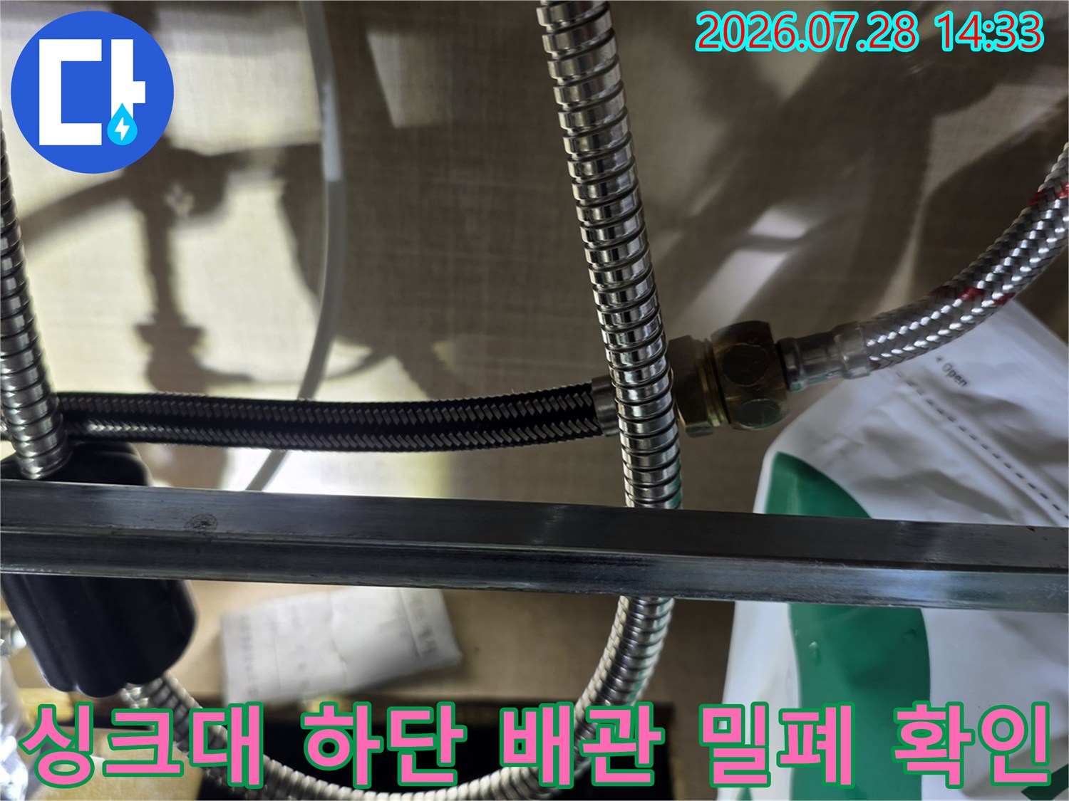 금속 주름관 호스가 너트로 연결되어 있는 싱크대 내부 배관 모습