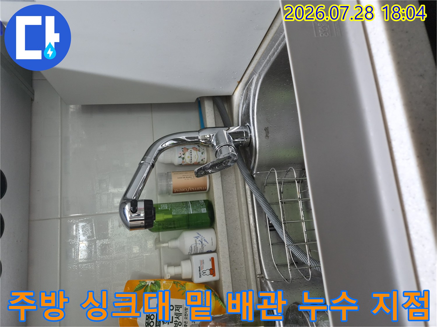 싱크대 아래 수전과 연결된 각종 호스 및 어댑터의 결합 상태 확인 장면