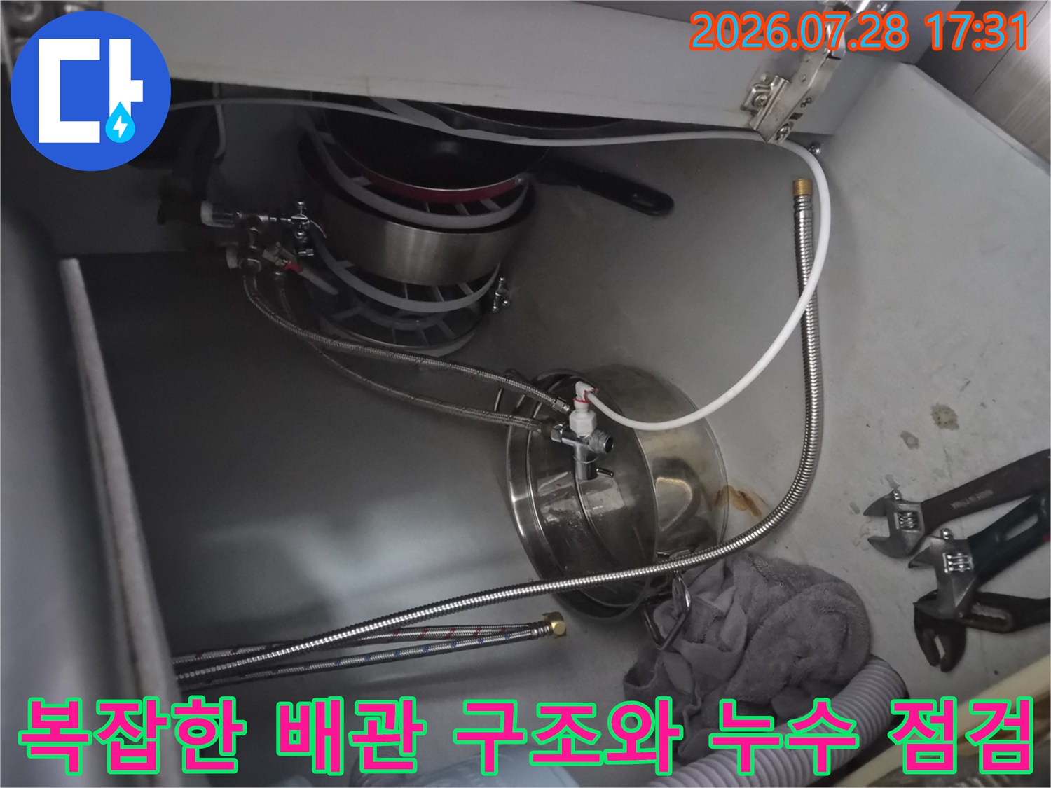 싱크대 하부의 복잡한 배관망과 식기세척기 연결부 상세 사진
