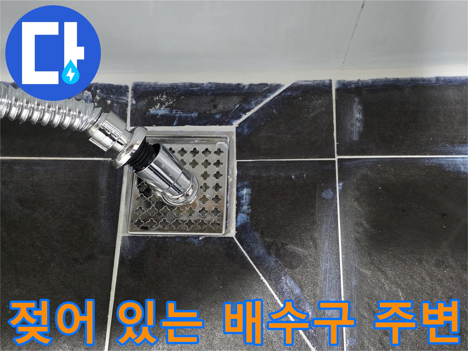 금속 유가 덮개와 인접한 타일이 물에 젖은 상태입니다.