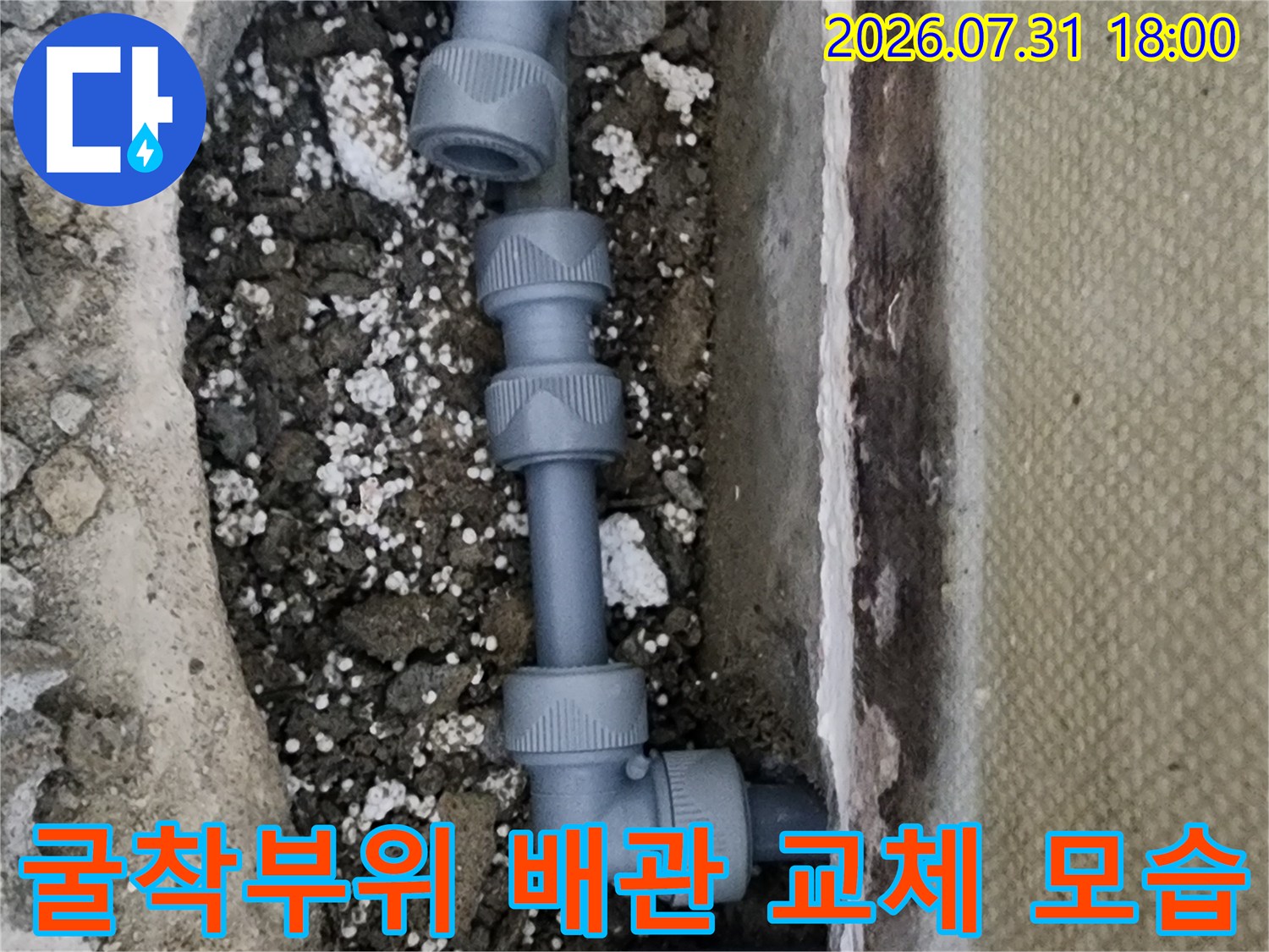 흙을 파내고 노출된 회색 배관과 연결 부속의 수리 현장
