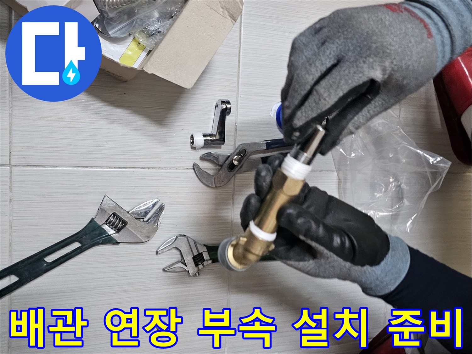 몽키스패너와 샤워기 연장 부품이 바닥에 놓여 있는 작업 현장