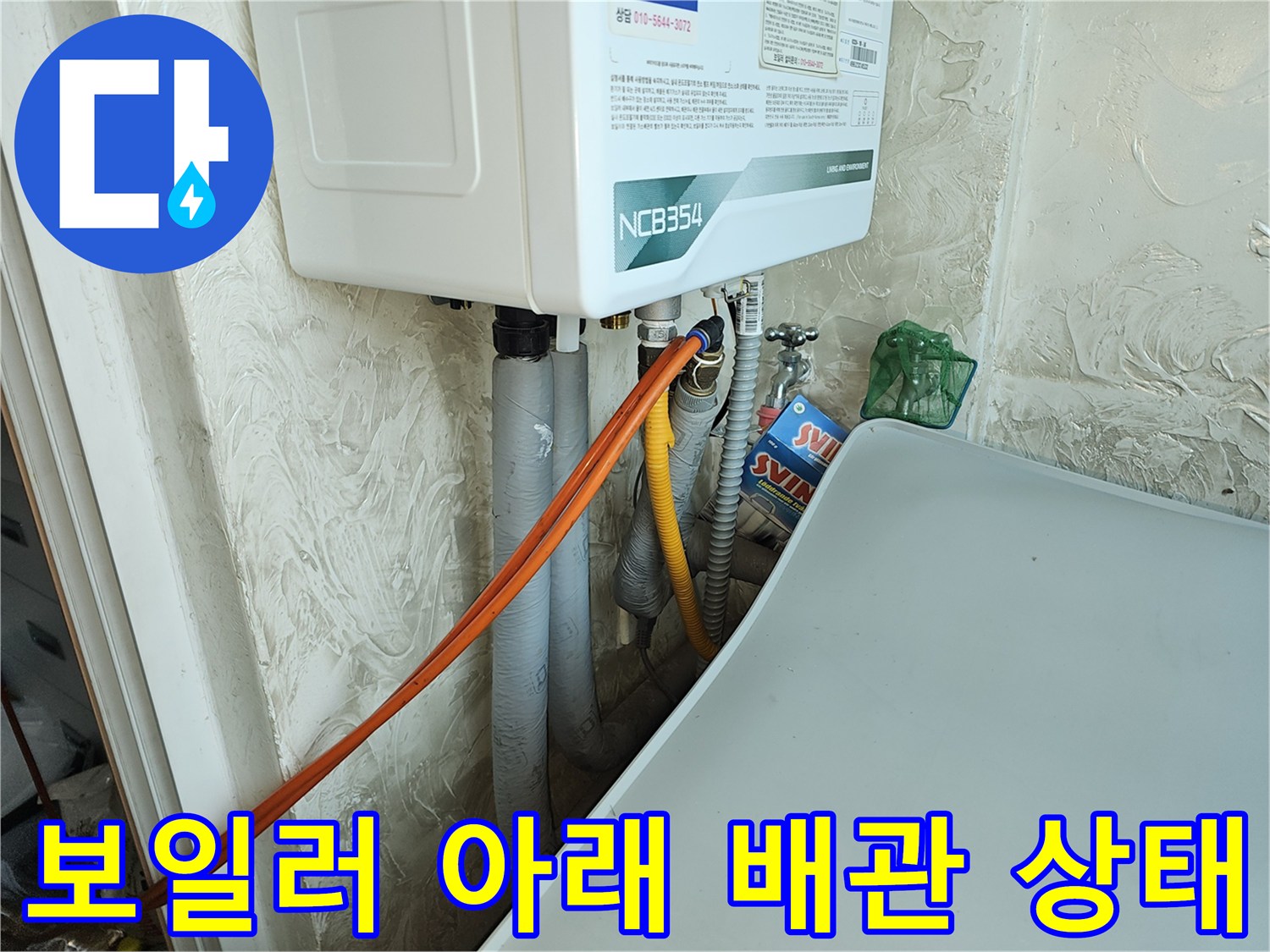 싱크대 하단의 보일러 배관과 주황색 유연 호스 연결 부위 모습