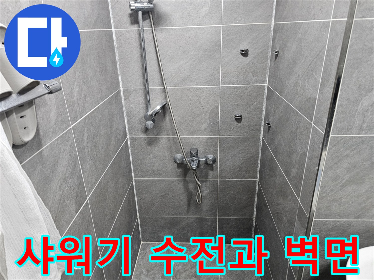 벽면에 설치된 샤워기 수전과 회색 타일 벽입니다.