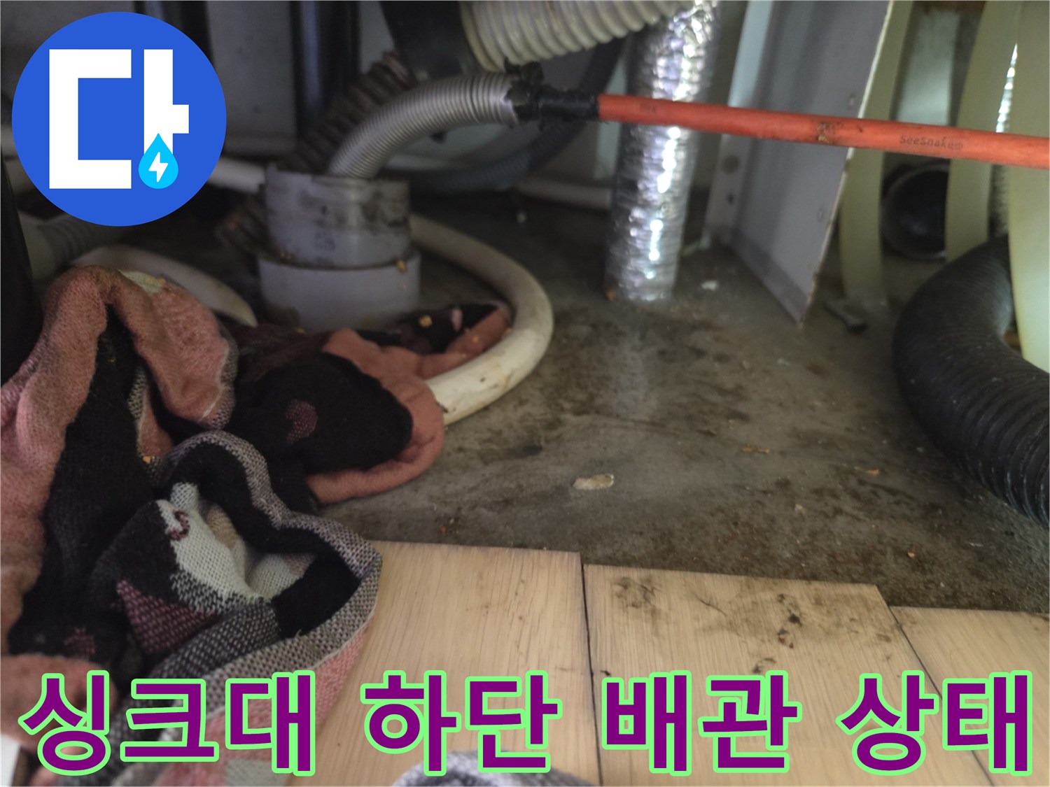 싱크대 아래 복잡한 배관 구조와 내시경 장비가 배치된 현장 모습