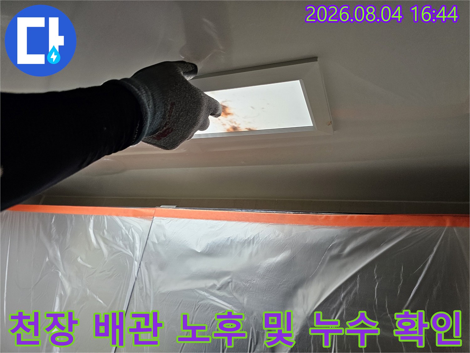 작업자가 장갑을 끼고 천장 점검구 내부의 젖은 배관 부위를 살피는 장면