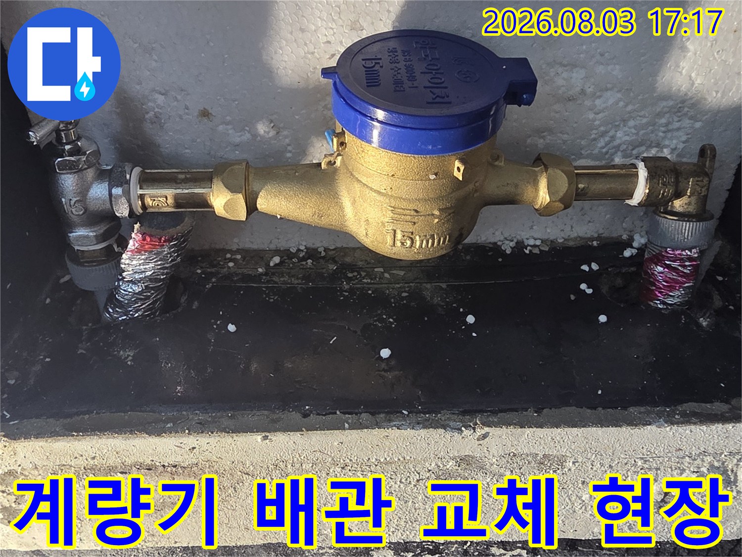 파란색 계량기와 금속 배관이 연결된 수리 현장 모습