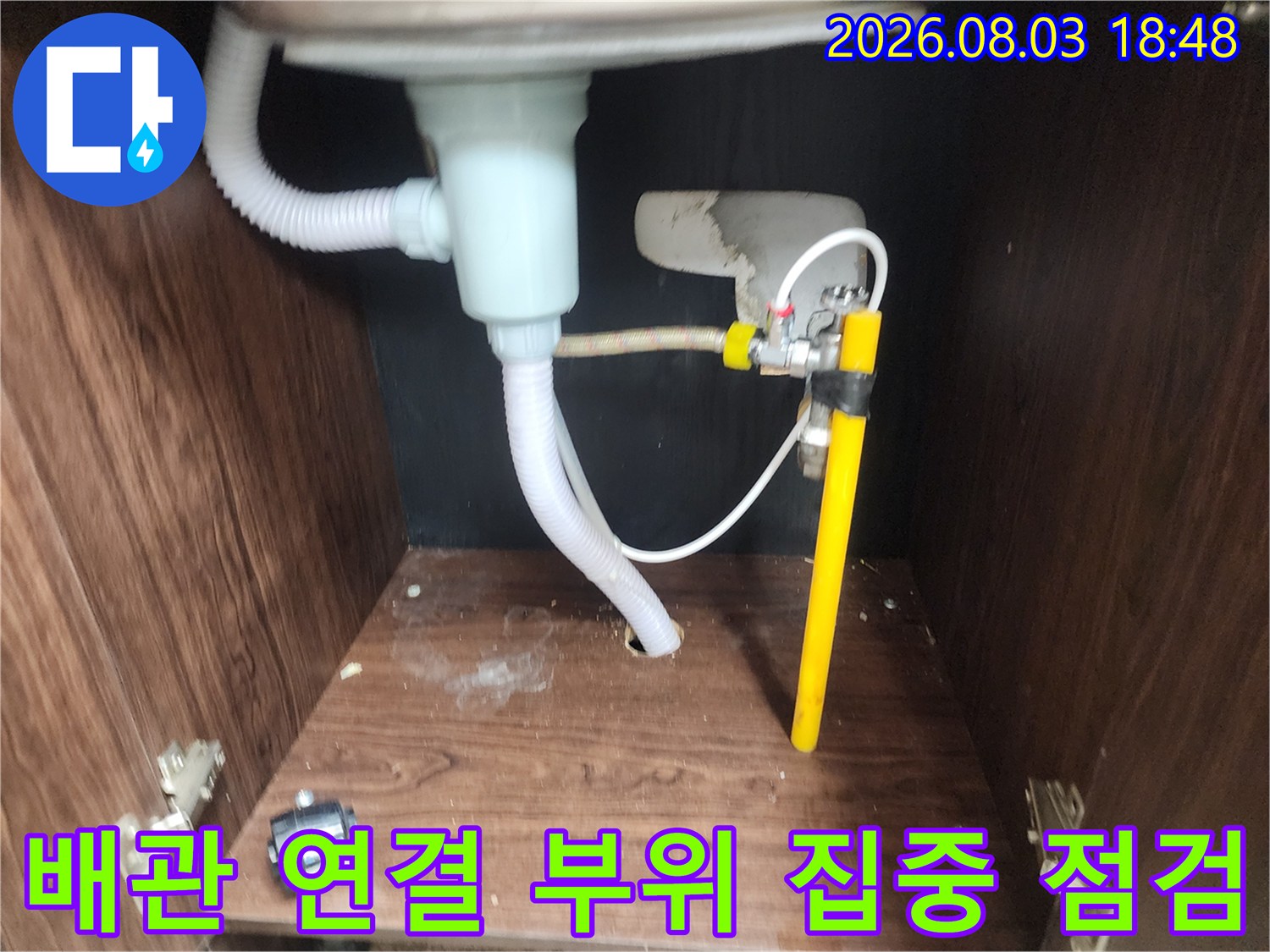 싱크대 아래 노출된 배관과 유연한 호스의 결합부