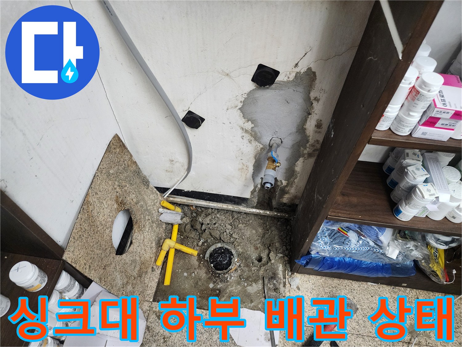 천안 동남구 현장의 싱크대 하부장 내부 노출된 배관과 벽면 균열 상태