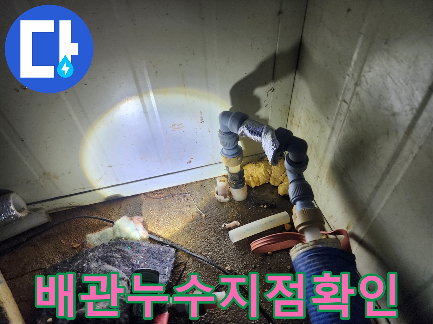 손전등으로 비춘 배관 연결 부위의 물샘 흔적